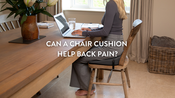 Person sitting on a chair cushion at the kitchen table working from home on a laptop
