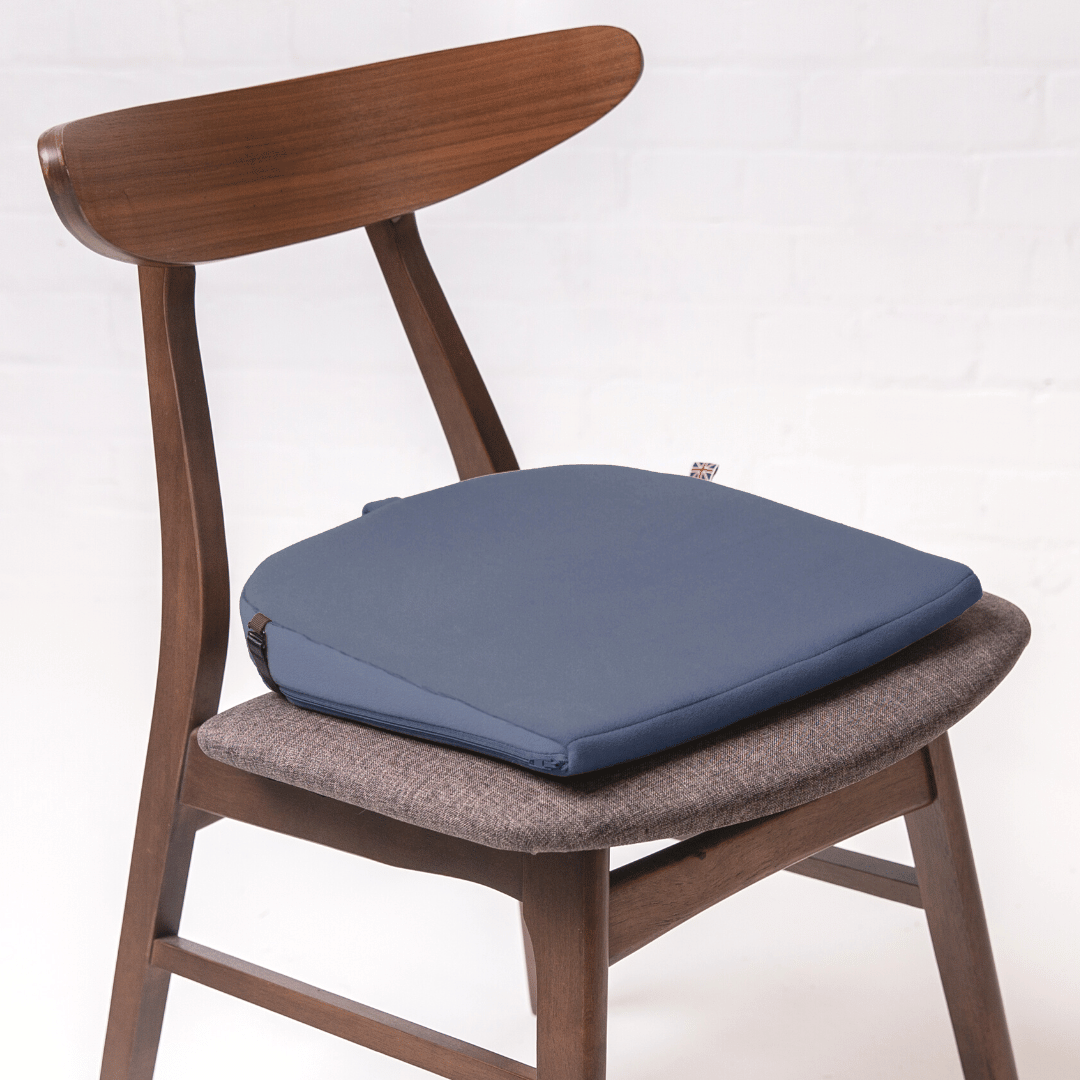 https://putnams.co.uk/cdn/shop/products/blue-navy-8-degree-sitting-wedge-tailbone-pain-back-posture-hips-knees-cushion-office-dining-chair-working-from-home-Putnams_1_1800x1800.png?v=1673528440